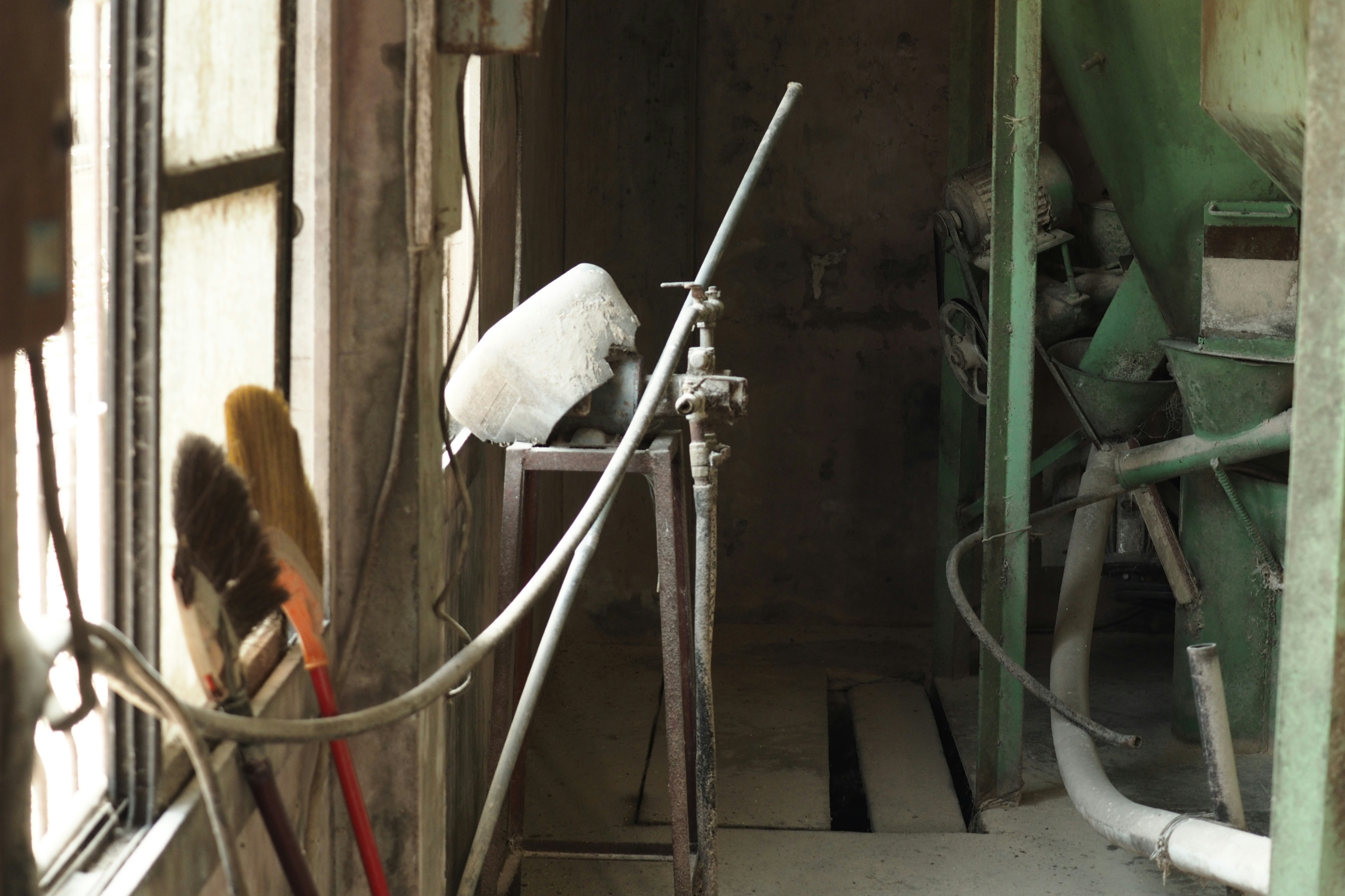 white and brown broom leaning on green metal door