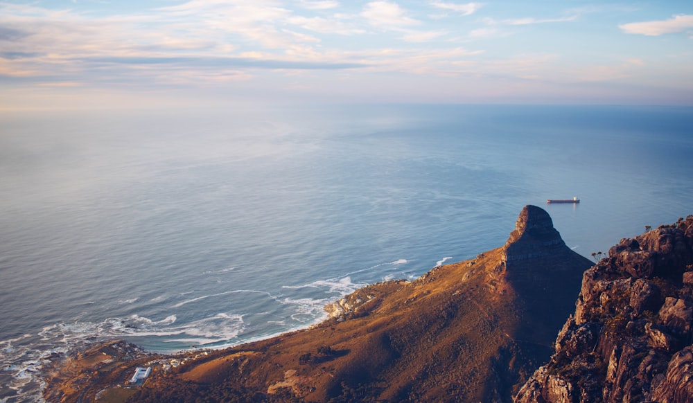 brown mountain beside blue sea during daytime