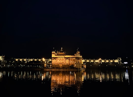 brown concrete building near body of water during night time in Harmandir Sahib India