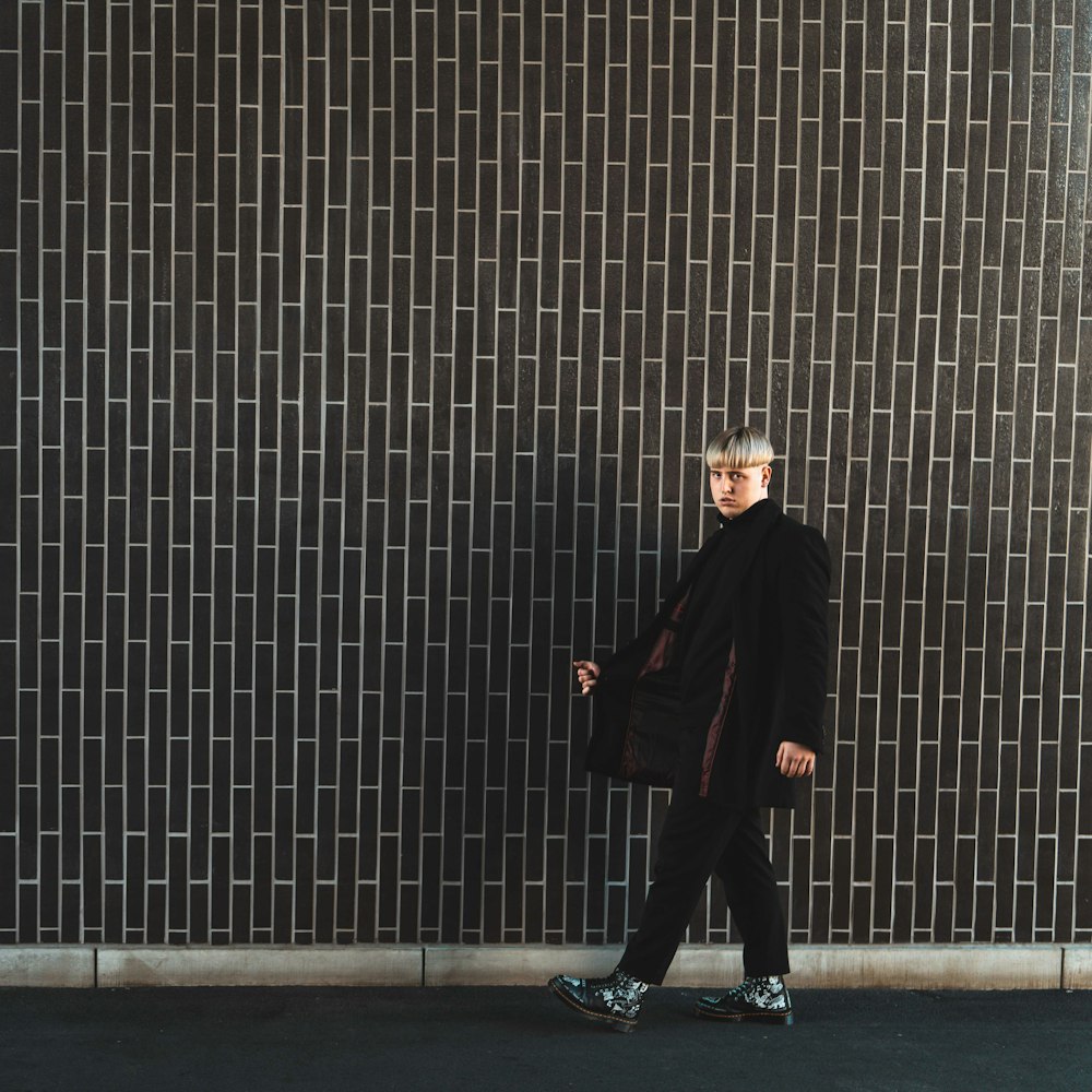 man in black coat standing on gray concrete floor