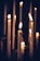 Multiple lit candles with melting wax are arranged in a dark, dimly lit setting, casting a warm glow and soft shadows, creating a peaceful and tranquil atmosphere.