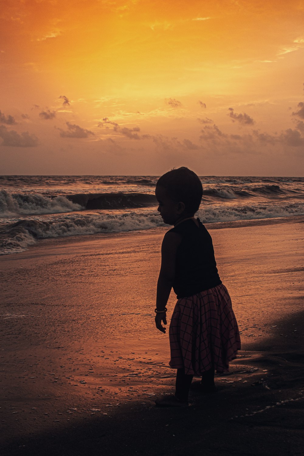 silhouette of woman standing on seashore during sunset