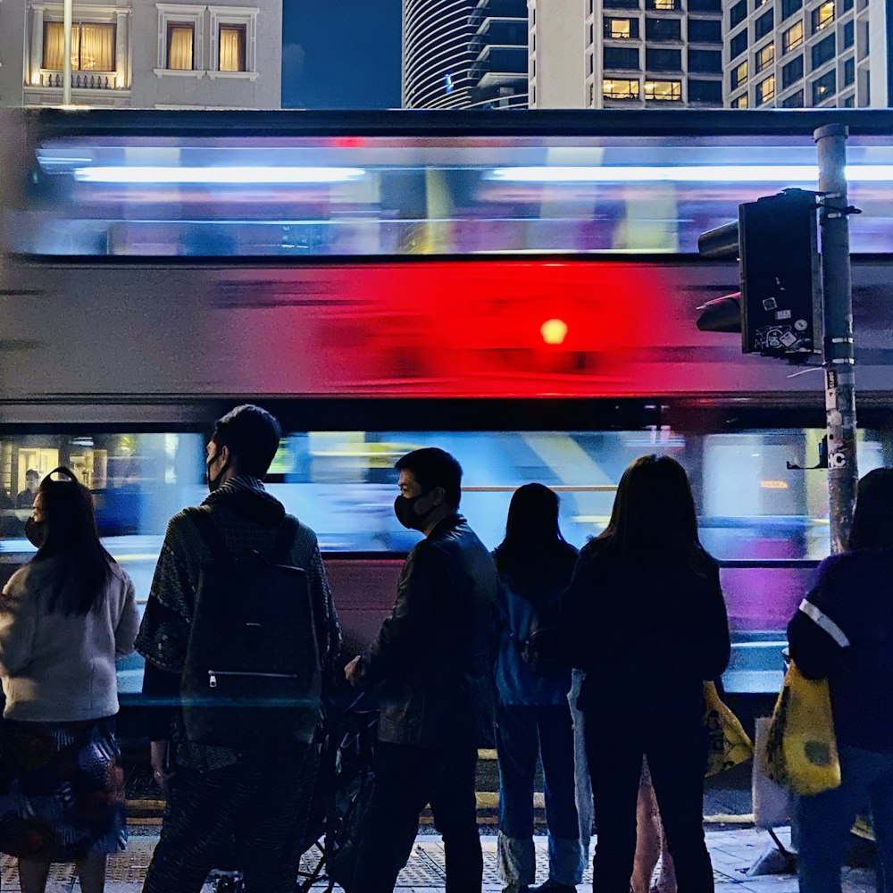 야간에 빨간색과 흰색 기차 앞에 서있는 사람들