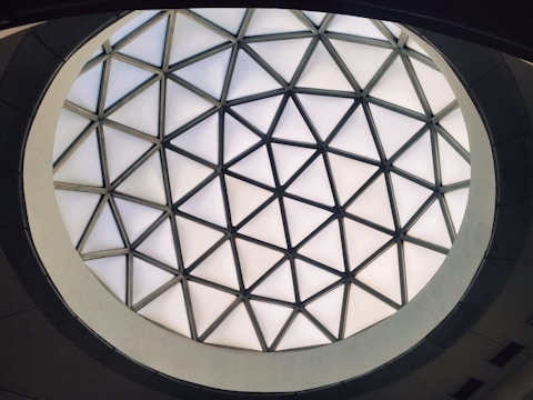 A geometric dome with triangular glass panels set in a symmetrical pattern, creating a bright, modern skylight. The structure forms a circular frame, providing a striking architectural feature.