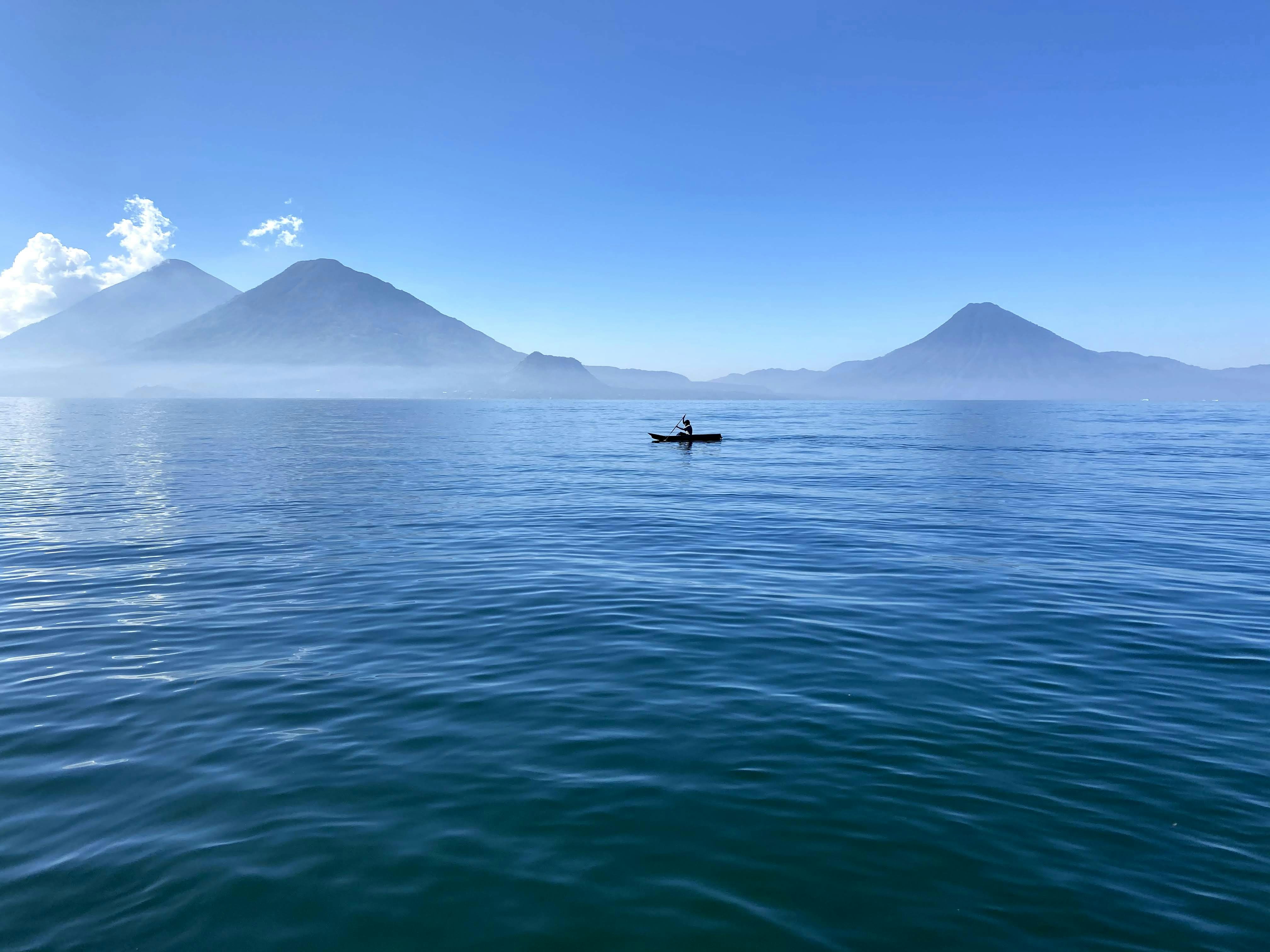 person in boat on sea near mountain during daytime, 