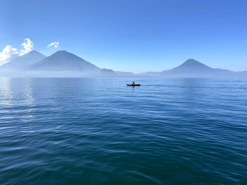 昼間、山の近くの海でボートに乗っている人