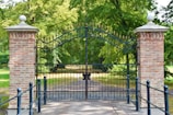 black metal gate near green trees during daytime