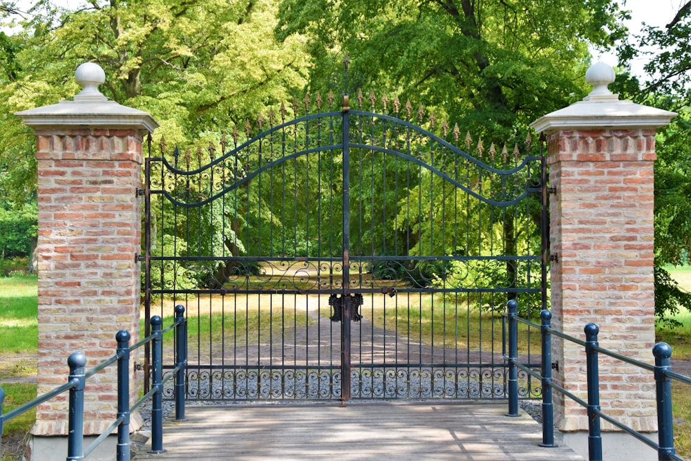 black metal gate near green trees during daytime