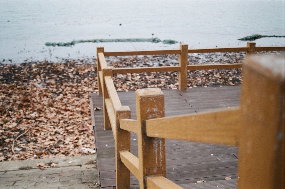 brown wooden bench on gray sand near body of water during daytime