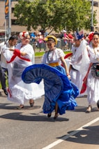 A joyful group dancing traditional Colombian cumbia in colorful costumes outdoors.
