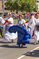 Children from diverse backgrounds dancing joyfully in a colorful outdoor festival.