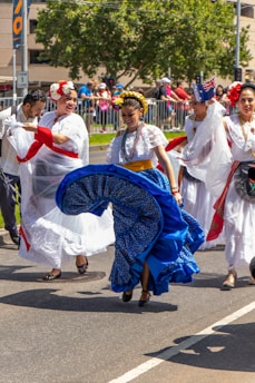 A joyful group dancing traditional Colombian cumbia in colorful costumes outdoors.