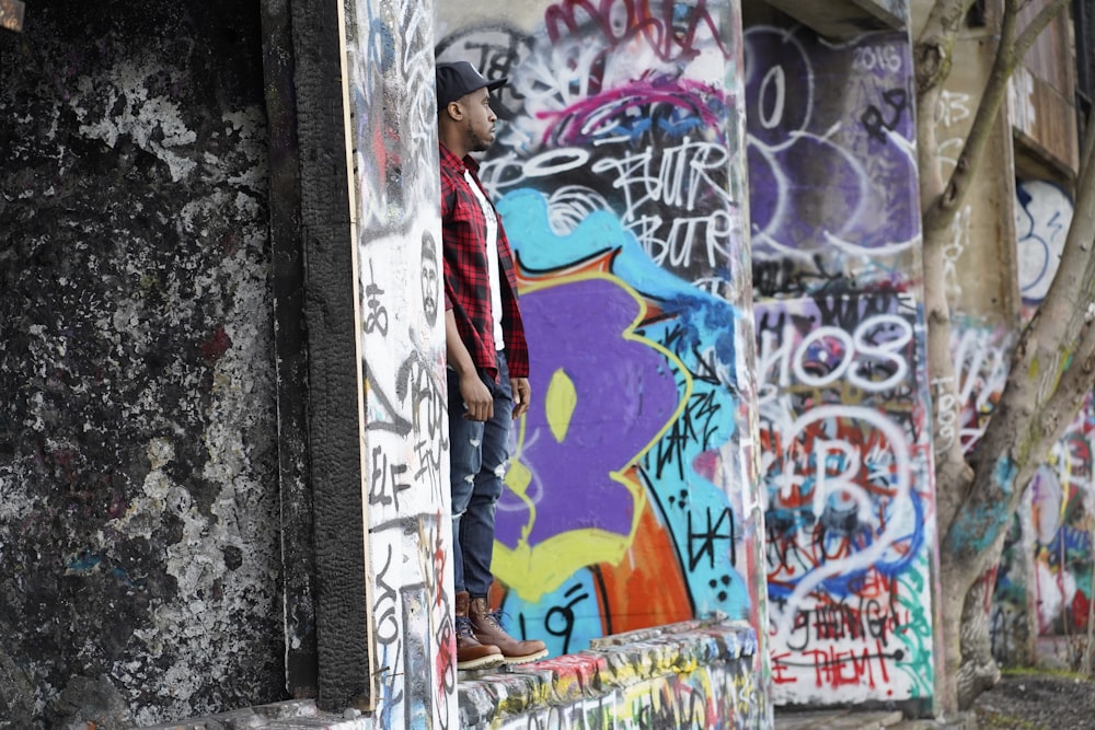 woman in red and white long sleeve shirt standing beside wall with graffiti