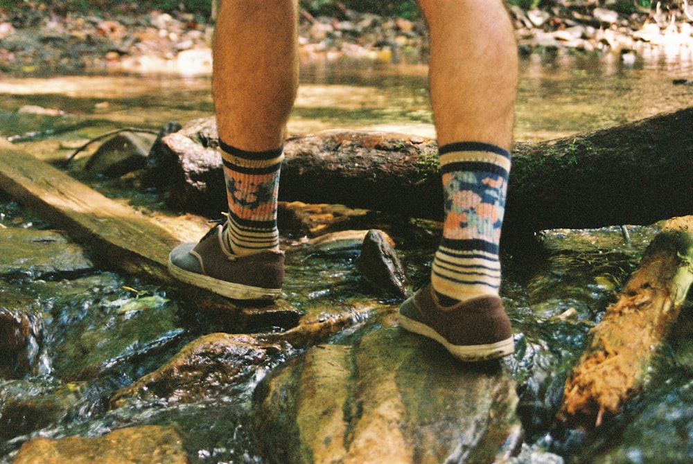 person wearing black and white socks and brown and black hiking shoes standing on brown wooden