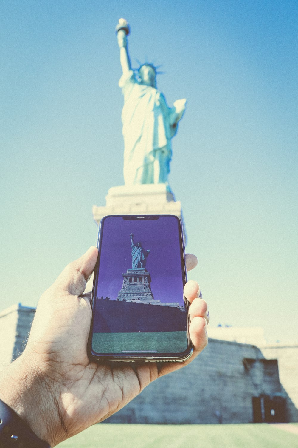 person holding black smartphone taking photo of statue of liberty