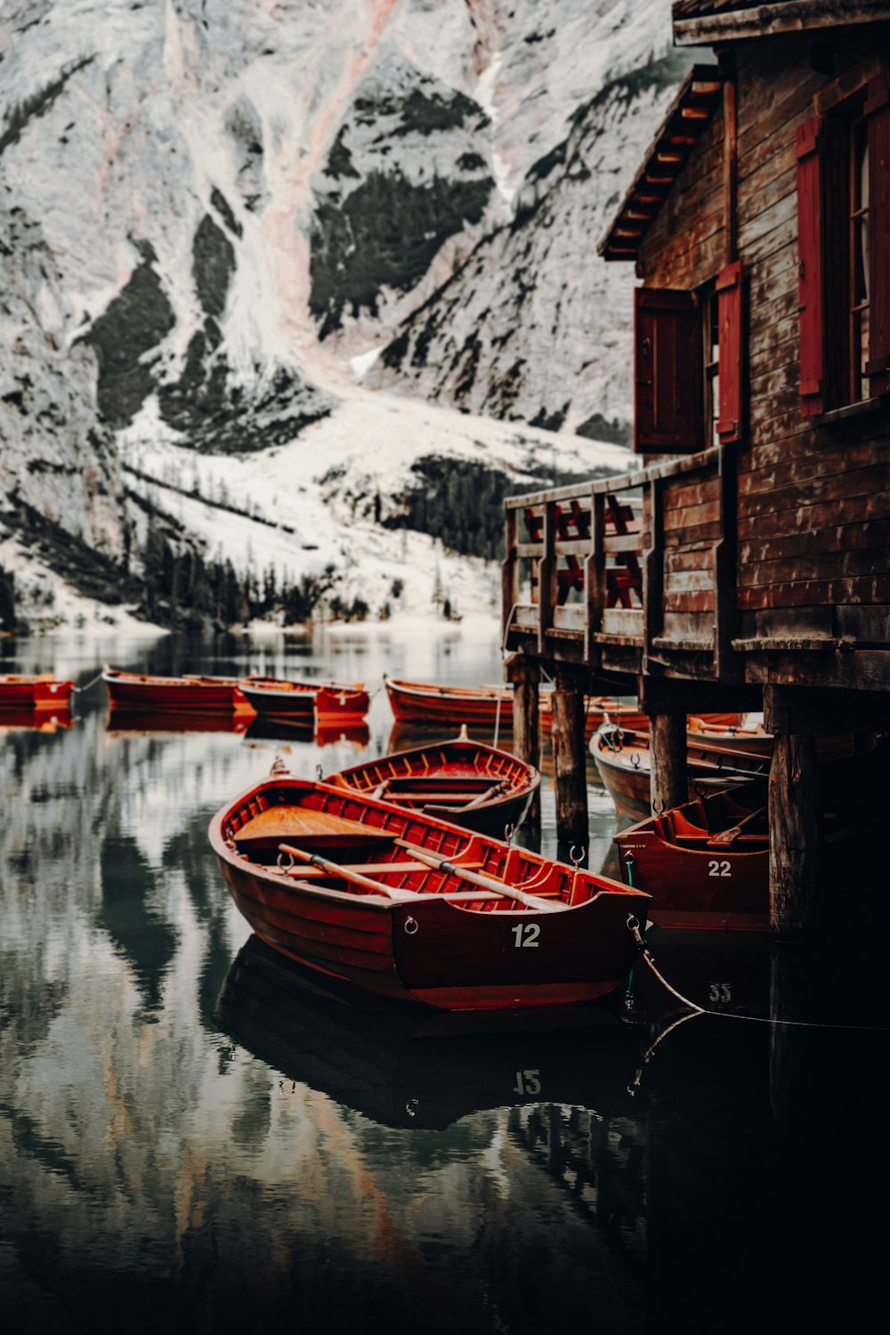 brown wooden boat on water near snow covered mountain during daytime