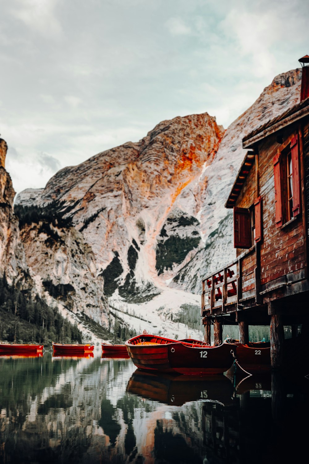 Rotes Boot auf Gewässern in der Nähe von braunem Holzhaus tagsüber