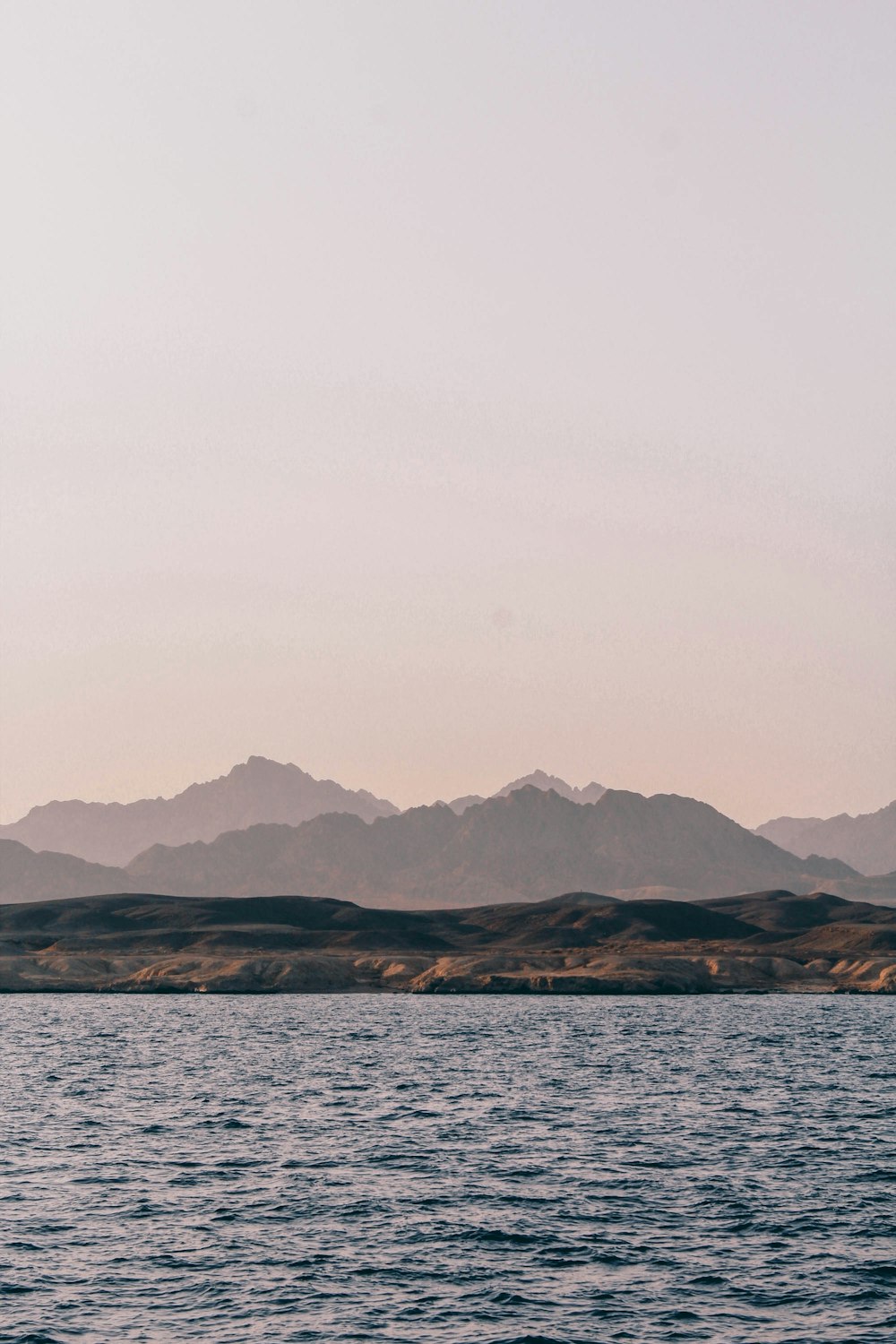 body of water near mountain during daytime