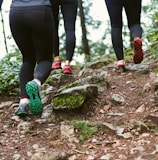 person in black leggings and green sneakers standing on brown rock