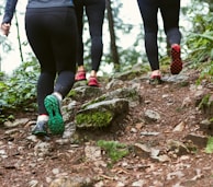 person in black leggings and green sneakers standing on brown rock