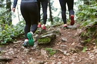 person in black leggings and green sneakers standing on brown rock