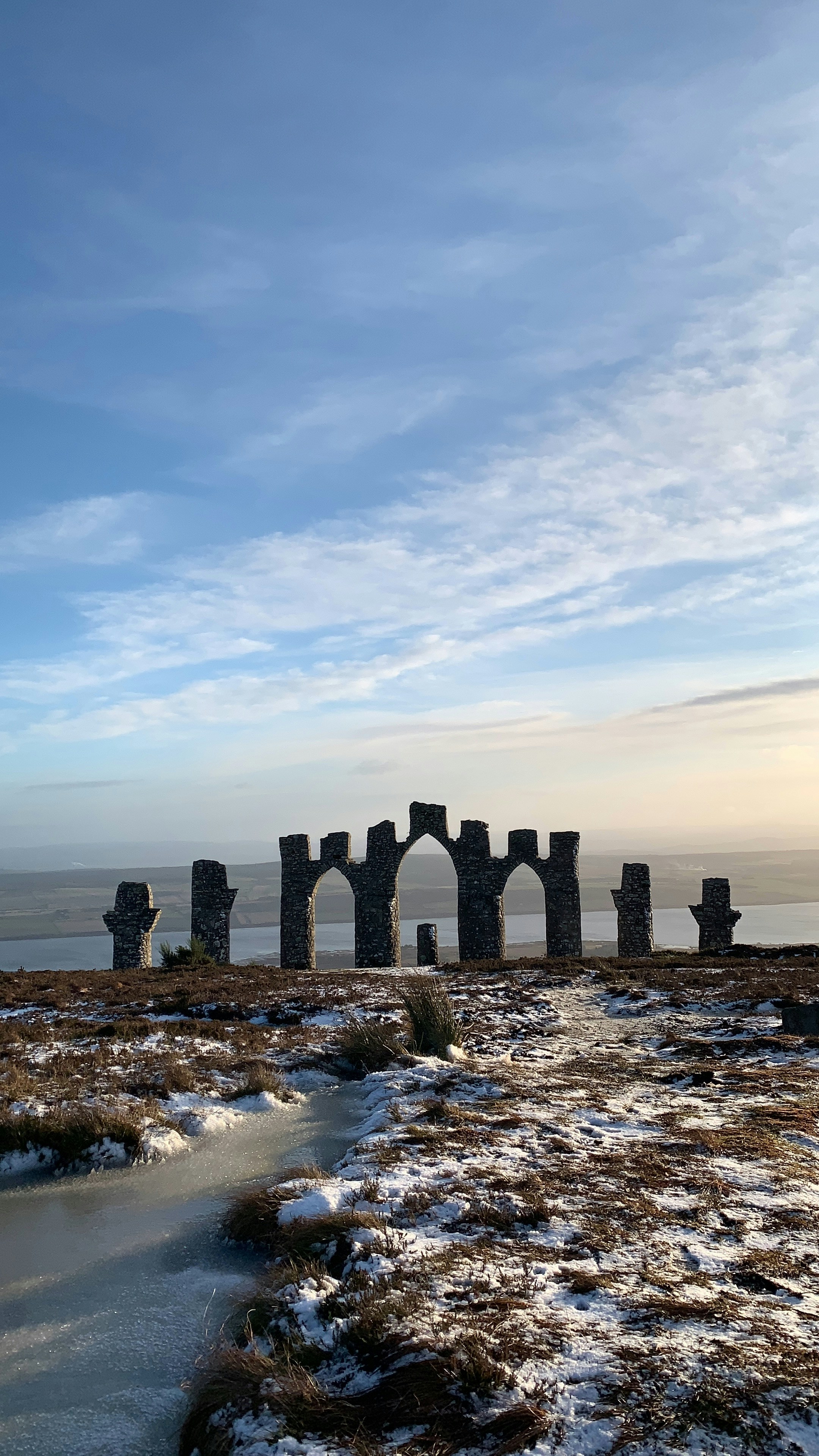 edifício de concreto cinza perto do corpo de água sob nuvens brancas durante o dia