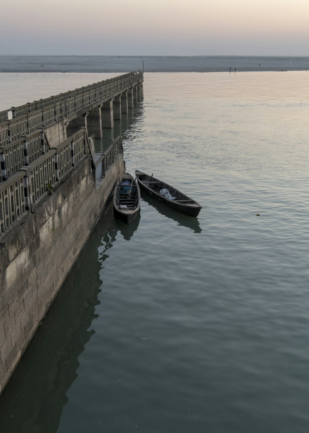 black boat on sea near brown concrete bridge during daytime