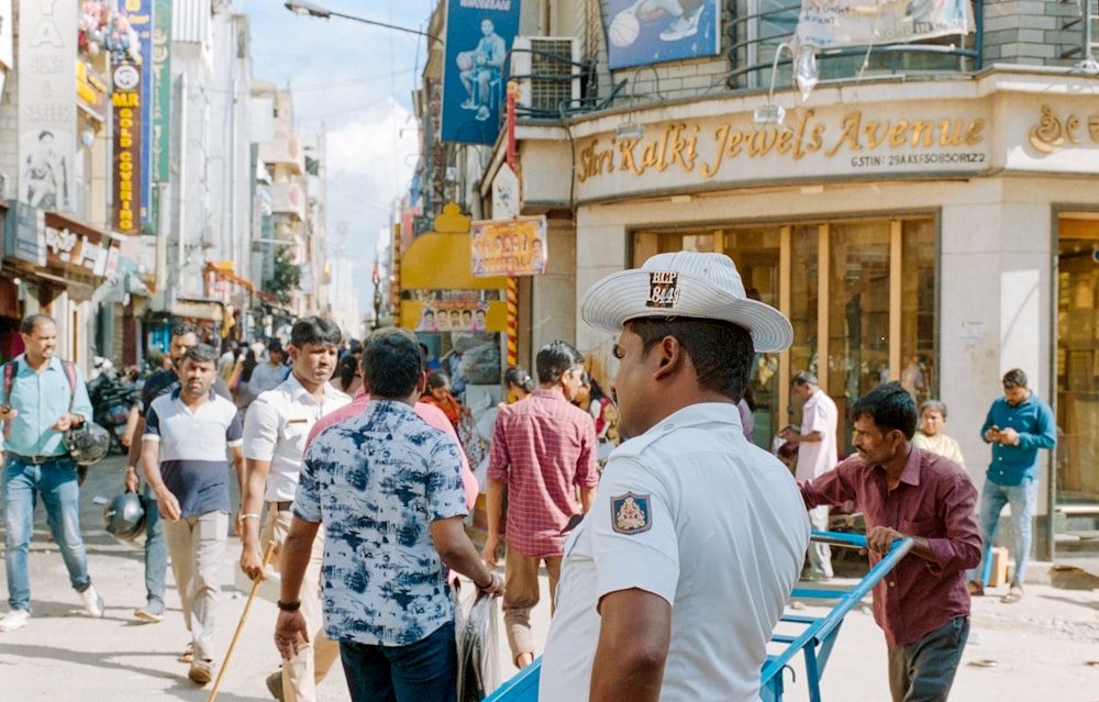 man in white t-shirt and brown hat standing on street during daytime