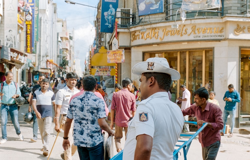 Mann in weißem T-Shirt und braunem Hut steht tagsüber auf der Straße