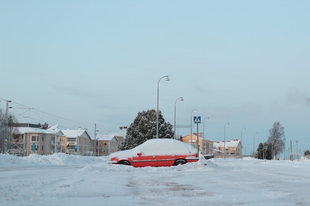 red car on road covered with snow during daytime
