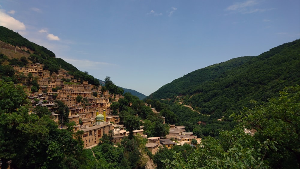 brown and white concrete buildings near green mountains under blue sky during daytime