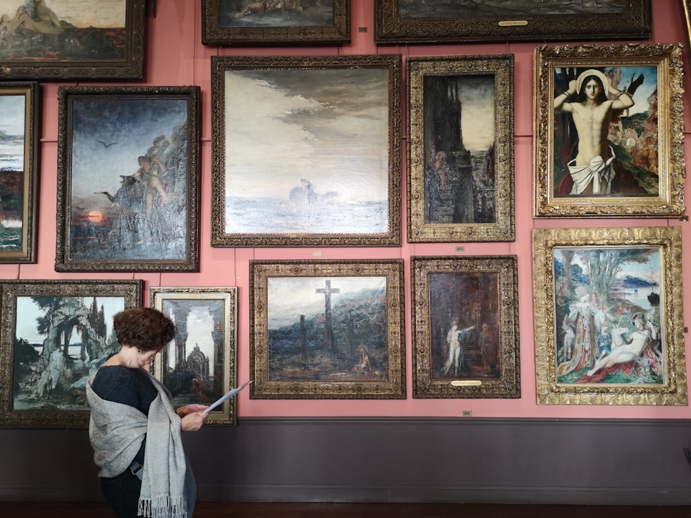 woman in white long sleeve shirt standing in front of paintings