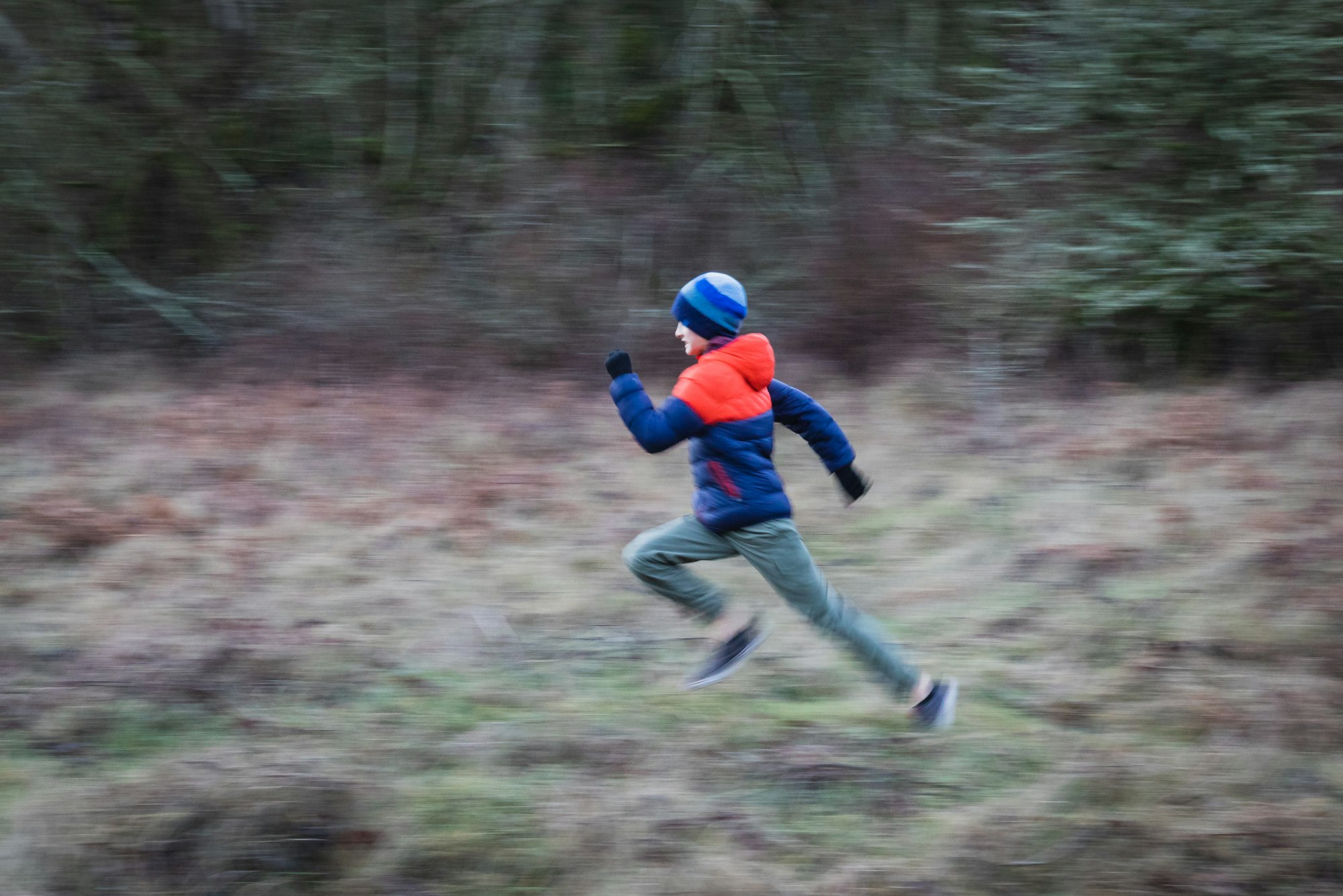 boy running fast in the forest outside during fall or winter