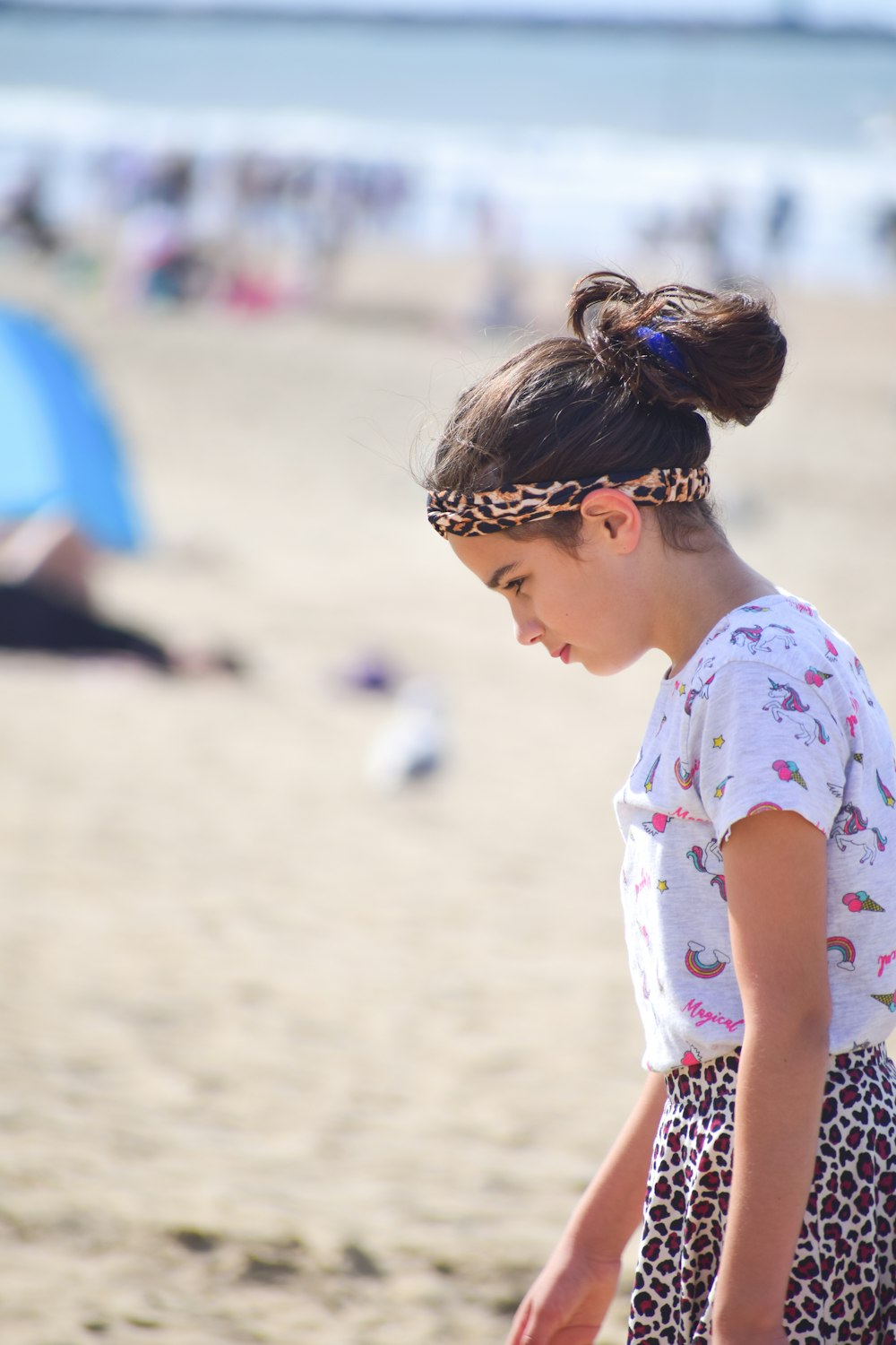 girl in white and blue floral shirt standing on beach during daytime