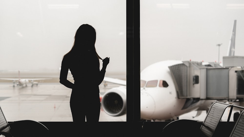 silhouette of woman standing in front of airplane