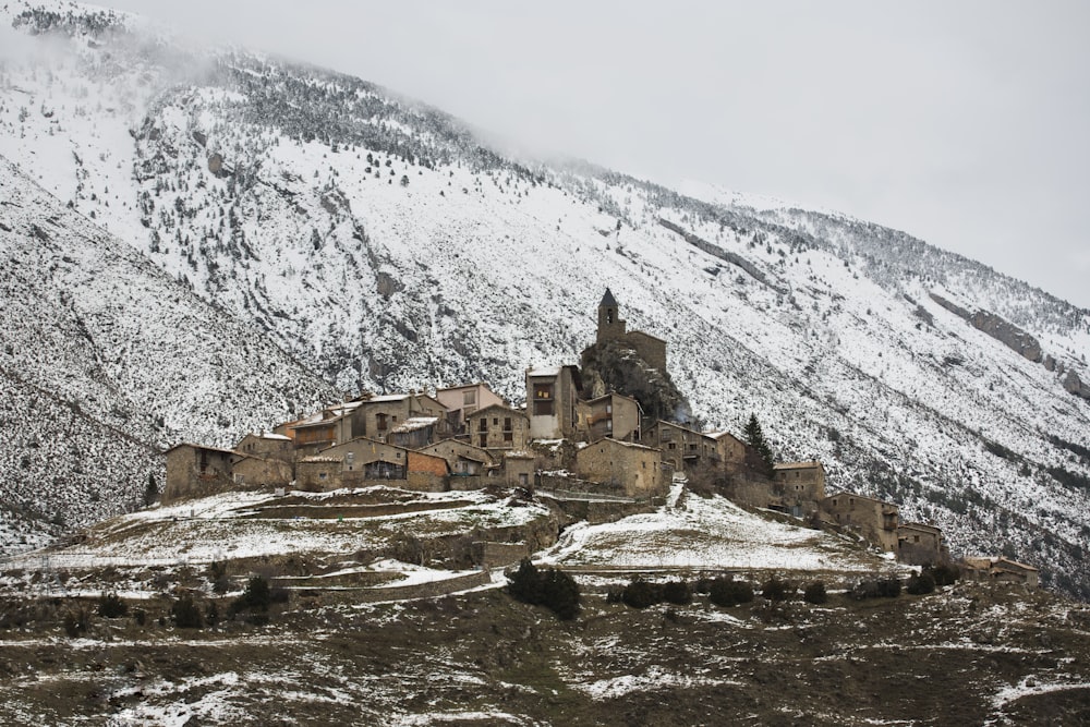 casas de concreto marrom perto da montanha coberta de neve durante o dia