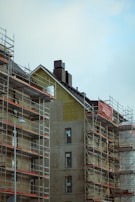 Exterior view of a building under construction with scaffolding and workers.
