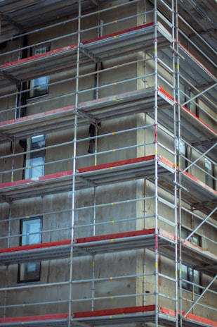 A sturdy metal scaffolding system securely installed around a multi-story building under construction.