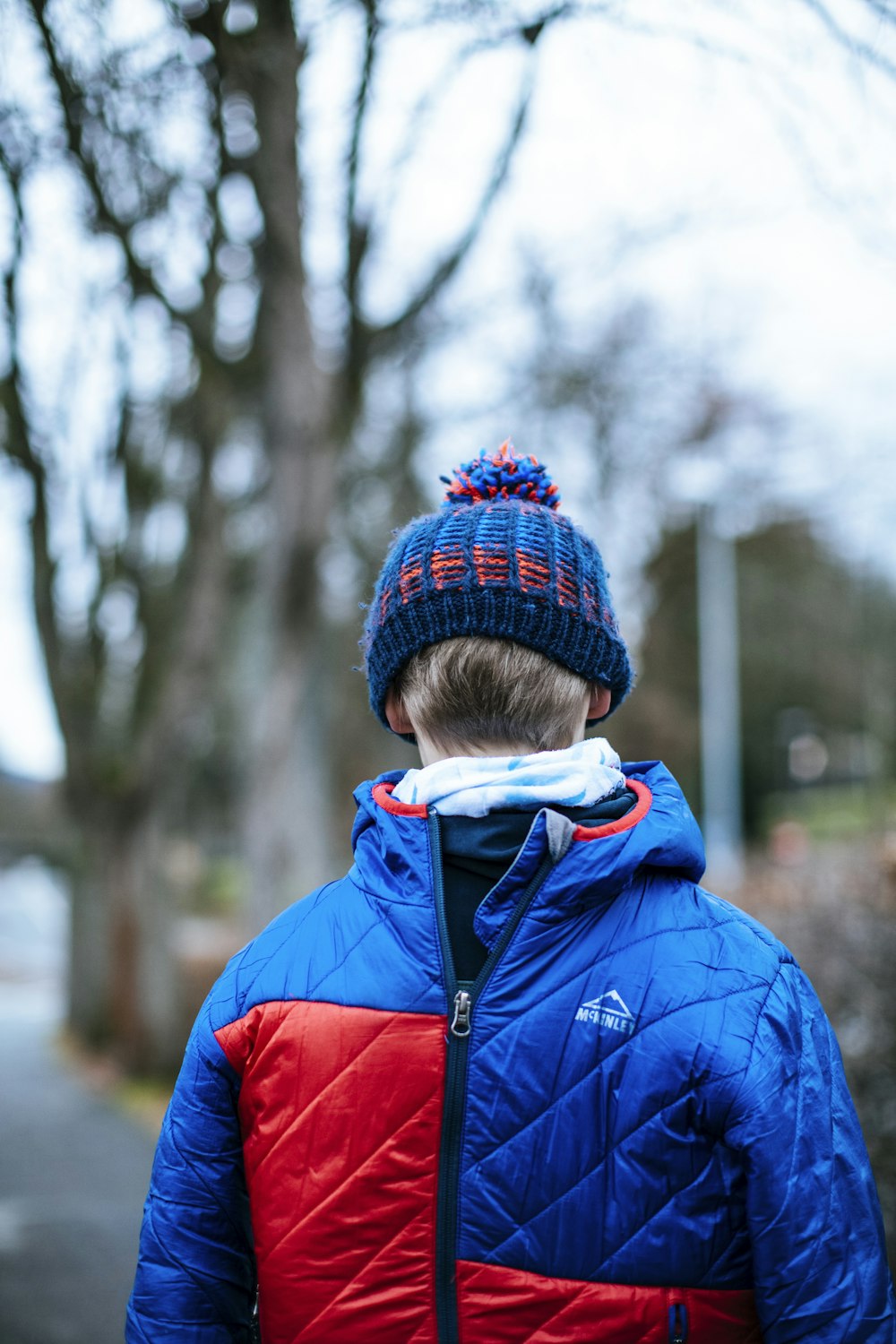 child in blue jacket and red knit cap