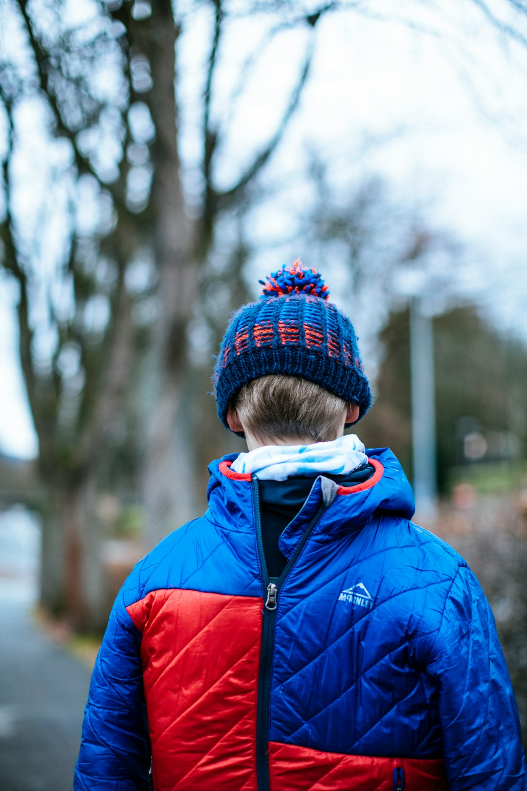 child in blue jacket and red knit cap