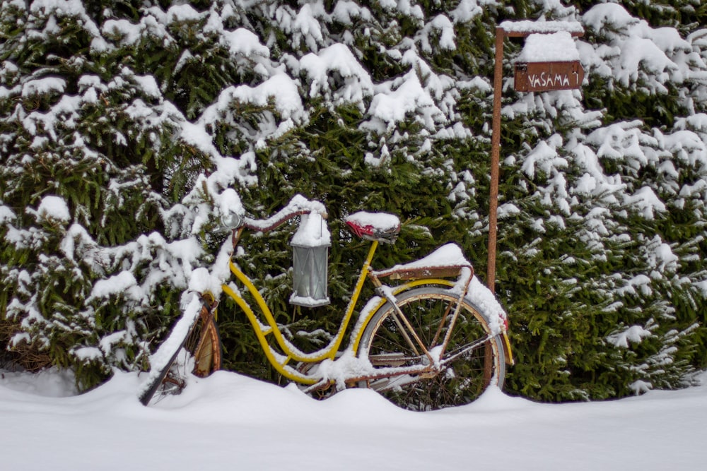 brown bicycle covered with snow near green trees during daytime