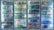 A well-lit row of refrigerated display cases filled with various bottled and canned beverages. The selection includes a wide range of drinks, organized neatly on shelves. Labels on the bottles and cans are visible, showcasing a variety of brands and flavors. The glass doors reflect some ambient light.