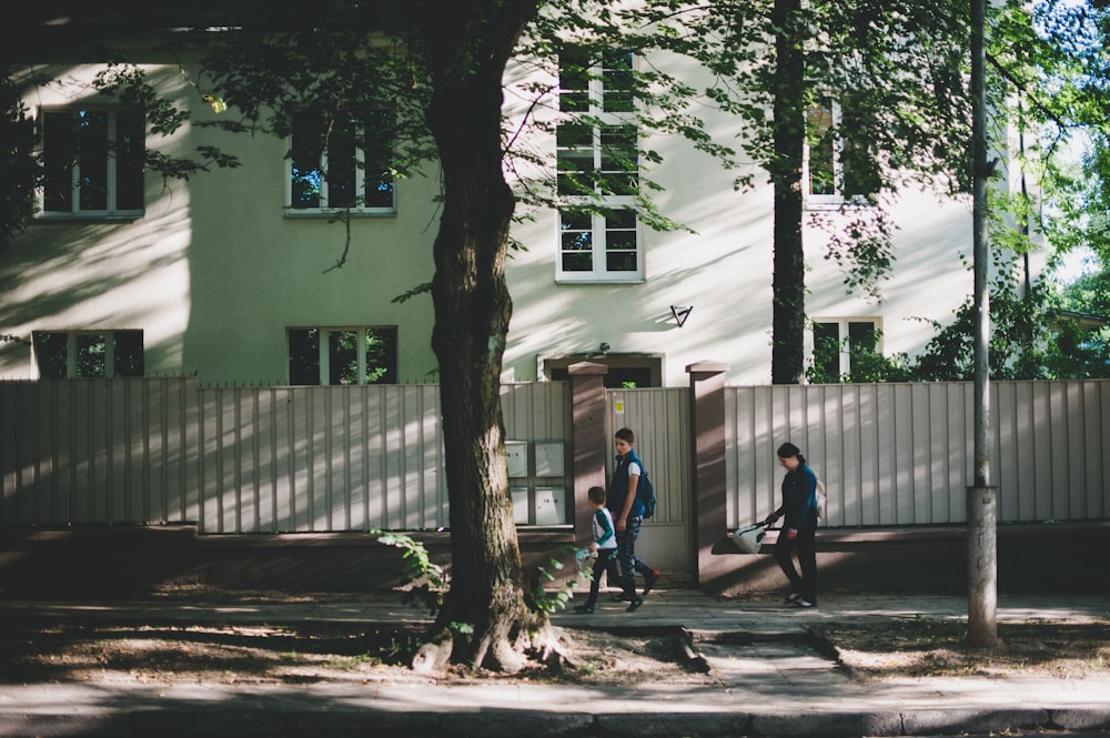 man in blue t-shirt and black pants walking beside green tree during daytime