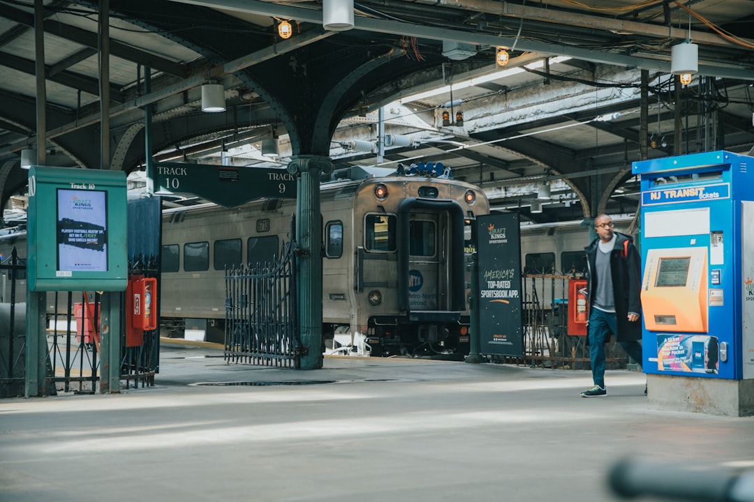 man in blue jacket standing beside train