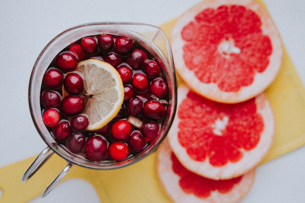 grapefruit, lemon, and cranberries in a pitcher on a cutting