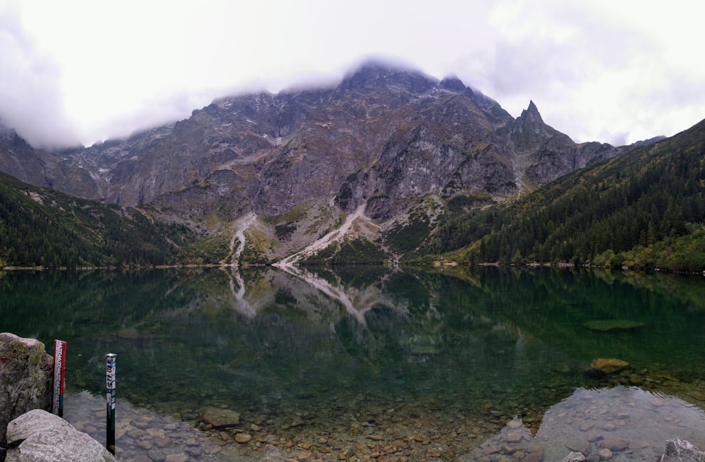 gray rocky mountain beside lake during daytime