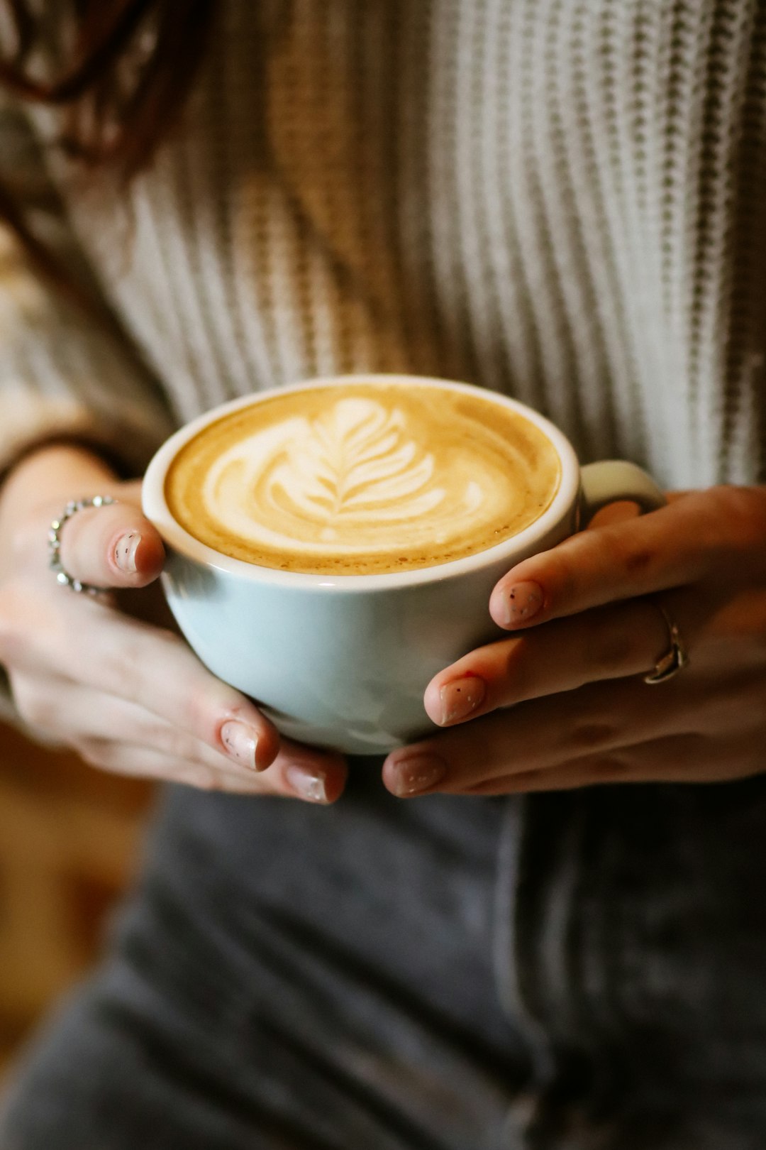 person holding white ceramic cup with cappuccino