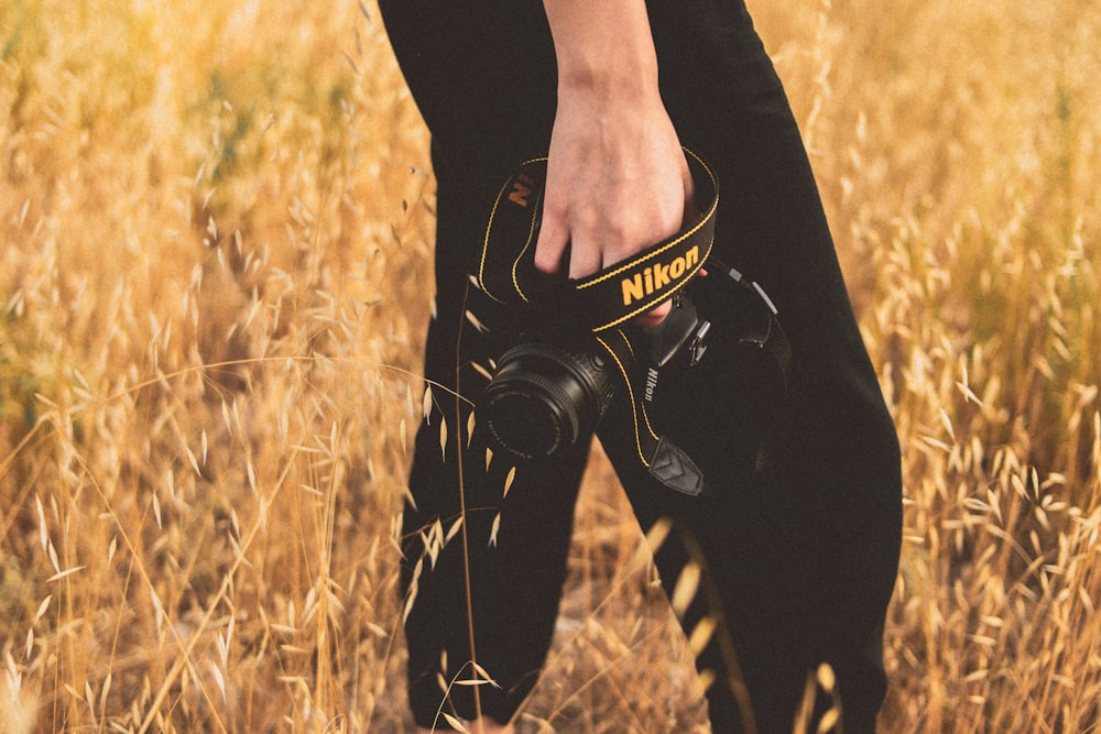 a person holding a camera in a field of tall grass