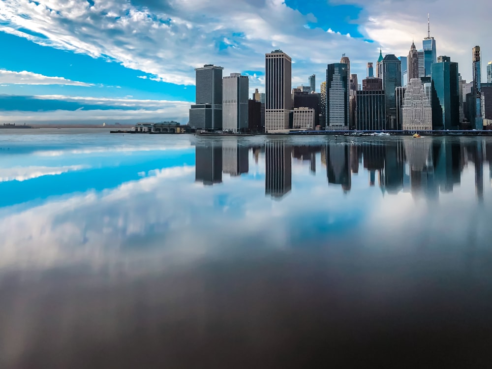 city skyline across body of water under blue and white sunny cloudy sky during daytime