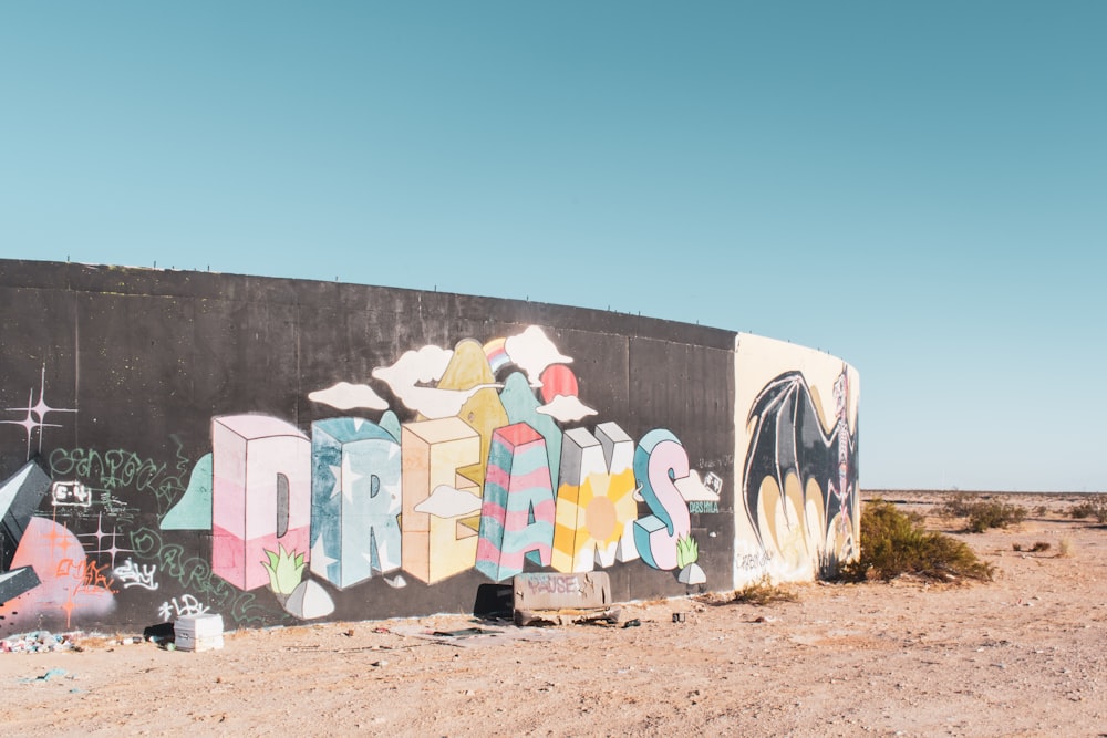 a wall covered in graffiti in the middle of a desert